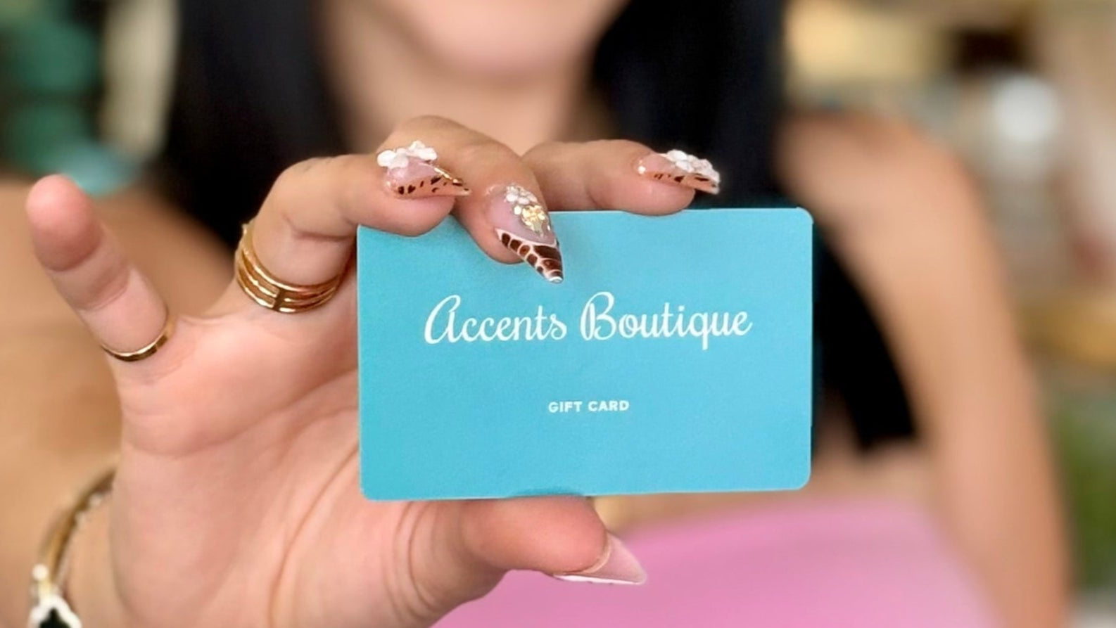 Hand holding a blue gift card with 'Accents Boutique gift card' printed on it.