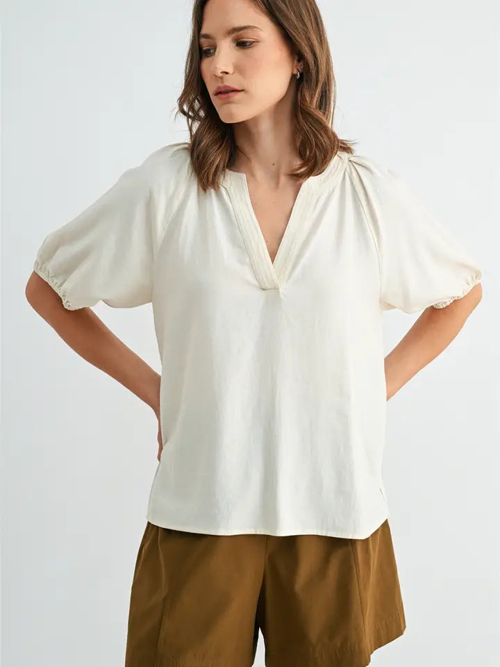 Woman wearing a white blouse and brown pants on a light gray background