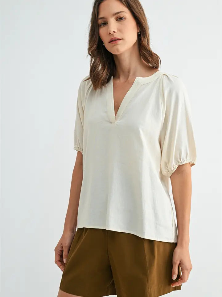 Woman wearing a white blouse and brown shorts on a light gray background