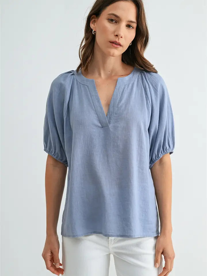 Woman wearing a light blue blouse with short sleeves on a white background