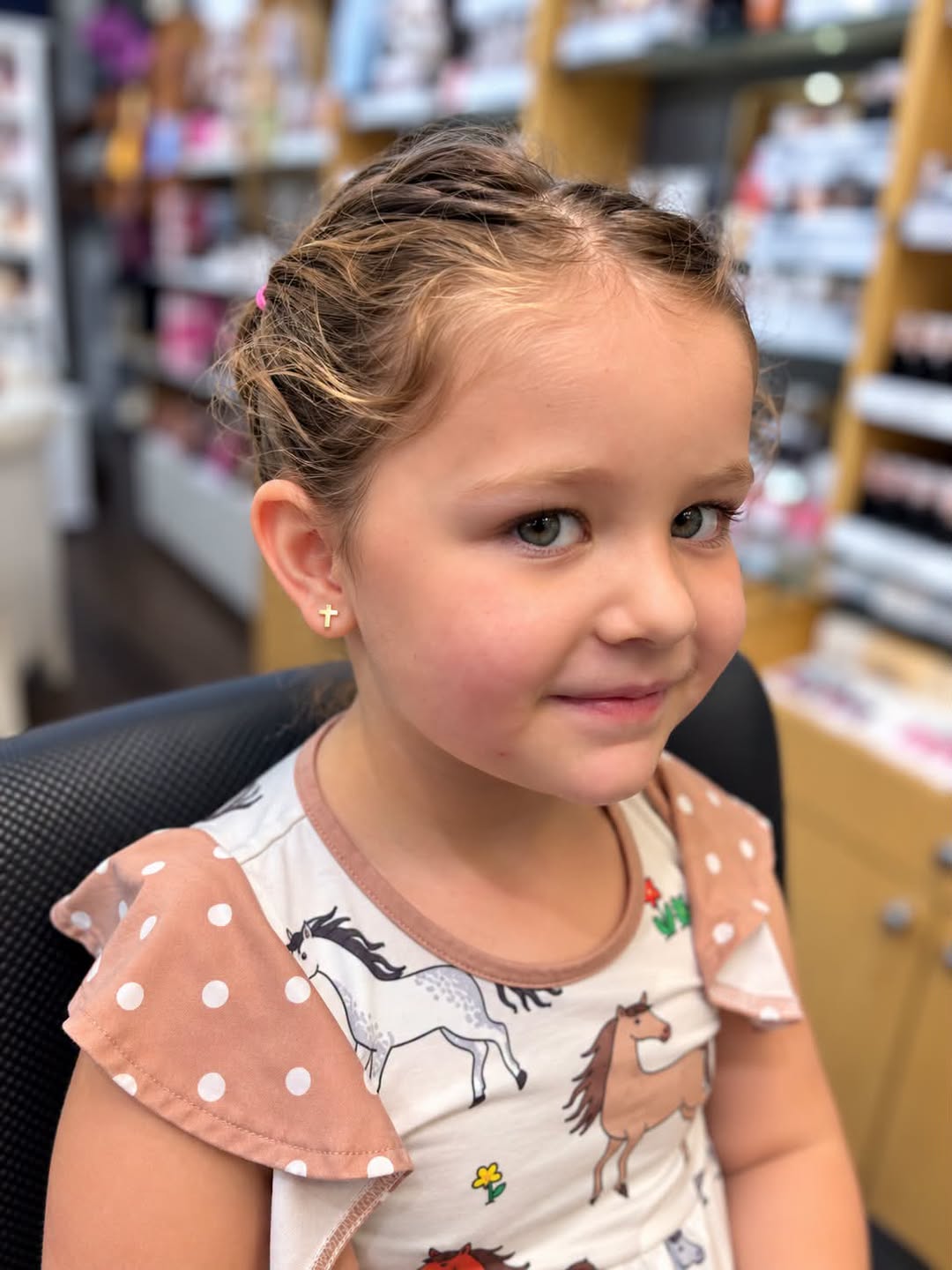 Young girl with cross earrings just pierced at Accents Boutique