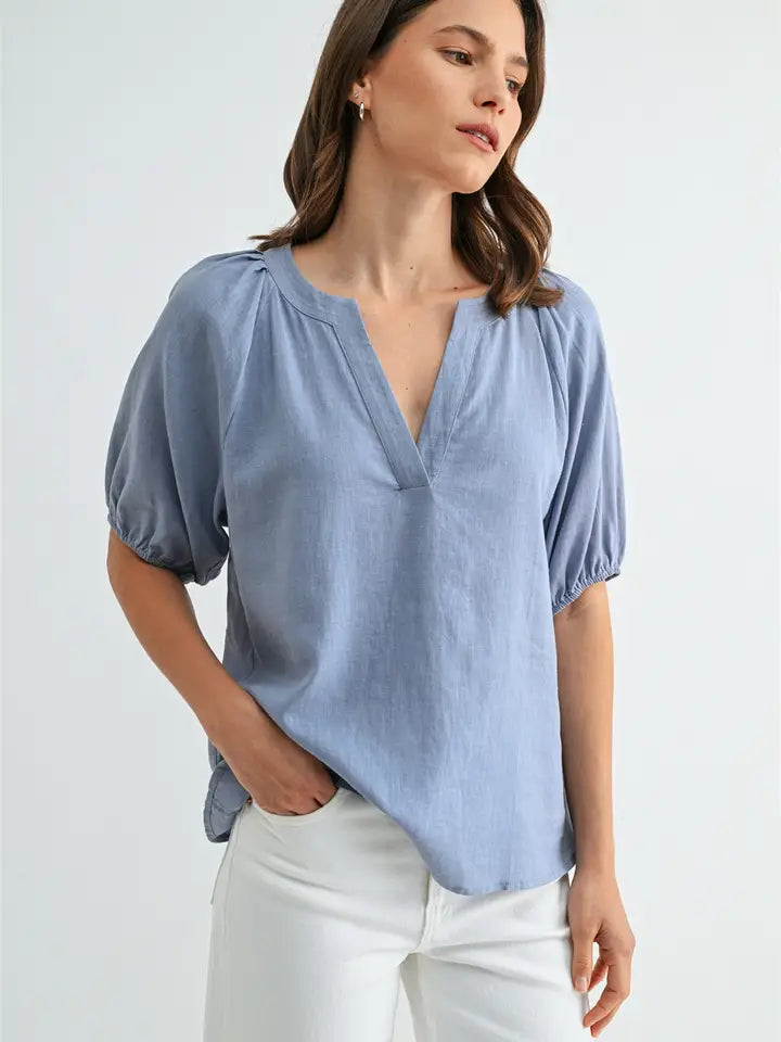 Woman wearing a light blue blouse with puff sleeves against a white background