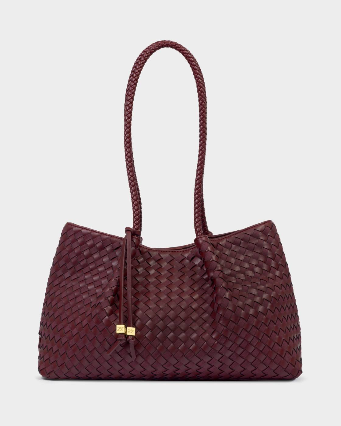 A woven leather shoulder bag in deep burgundy with braided top handles and a small gold-tone hardware accent, shown against a light gray background.